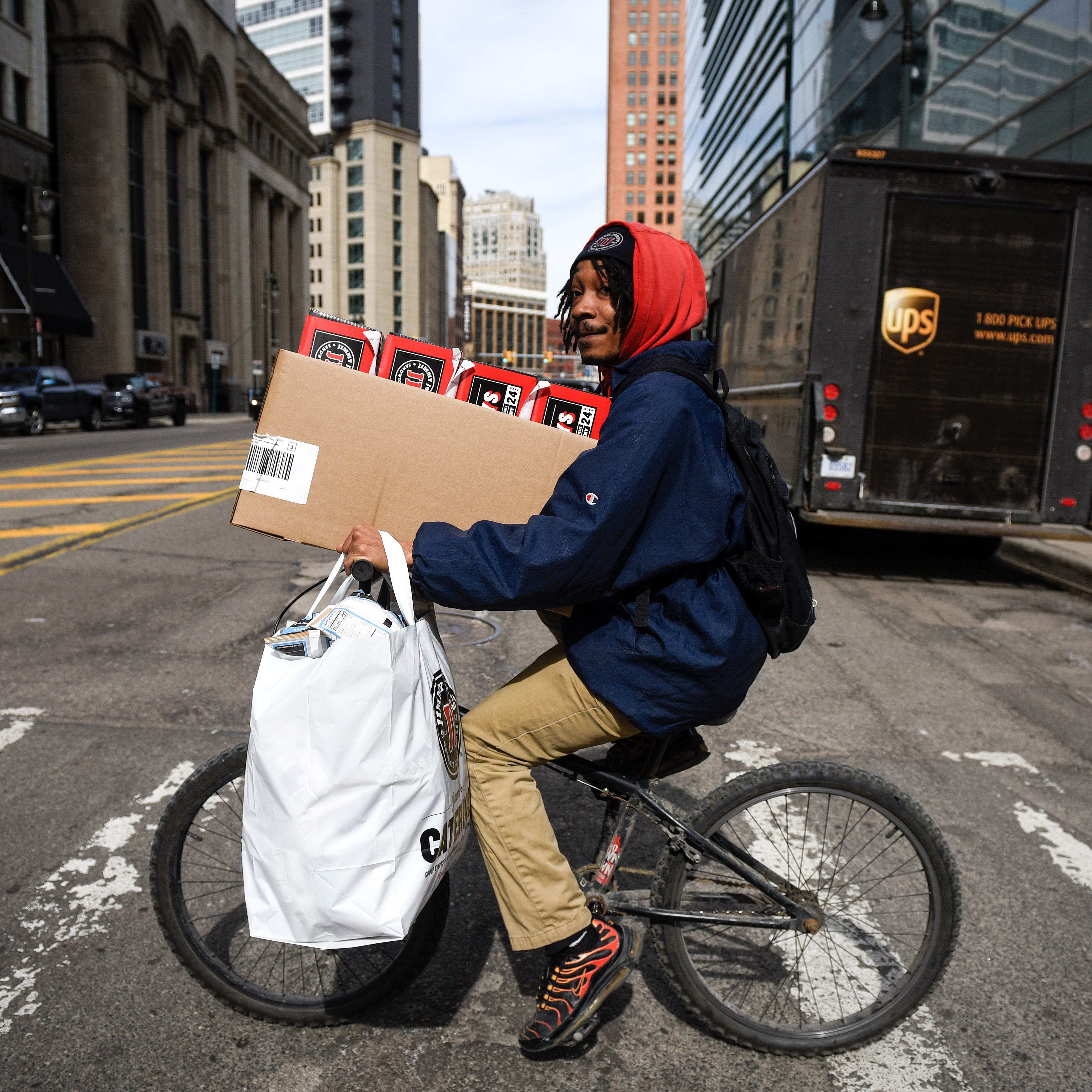 William Polk, a delivery person for Jimmy John's, checks for traffic as he crosses Griswold Street while traveling on W. Fort Street in downtown Detroit, Monday, March 16, 2020. "We have more orders than I thought we would because everybody's working from home," Mr. Polk said. "We're like the only ones open. So far it's like a normal day." 