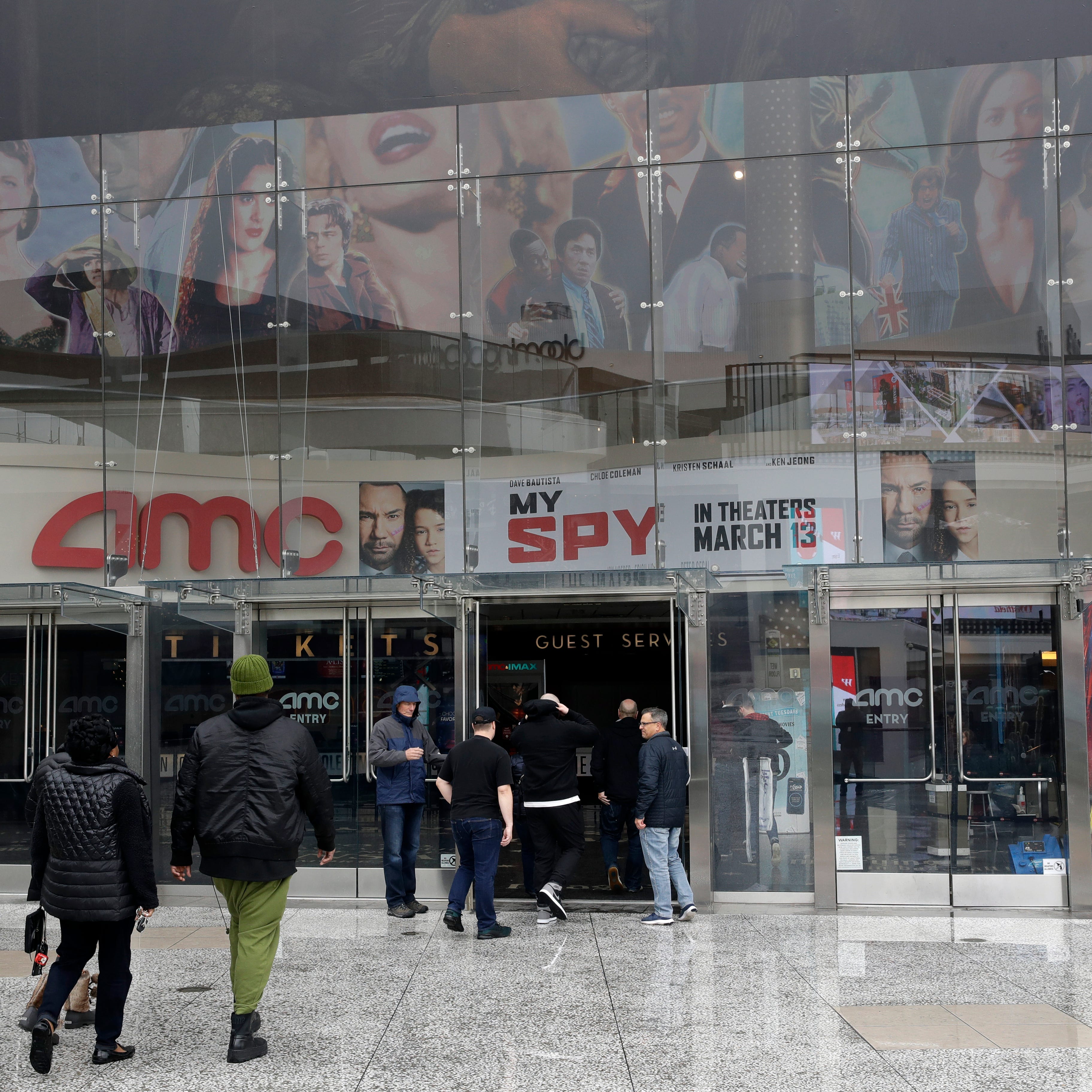 People enter an AMC theater March 14, 2020, in Los Angeles.