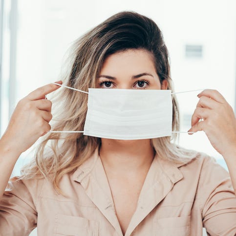 Portrait of woman wearing surgical mask at home. Covid-19, coronavirus and quarantine concept.