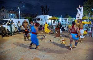 a group of people playing instruments and performing on a stage: Members of Mexican rock band Los Cogelones perform an Aztec ritual dance with friends in the streets of Ciudad Nezahualcoyotl